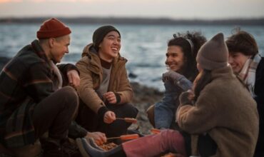 Friends enjoying a cozy lakeside campfire gathering during winter holidays at Lake Keowee