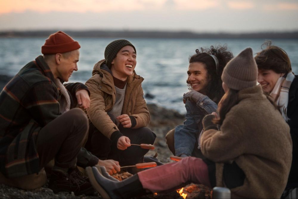 Friends enjoying a cozy lakeside campfire gathering during winter holidays at Lake Keowee